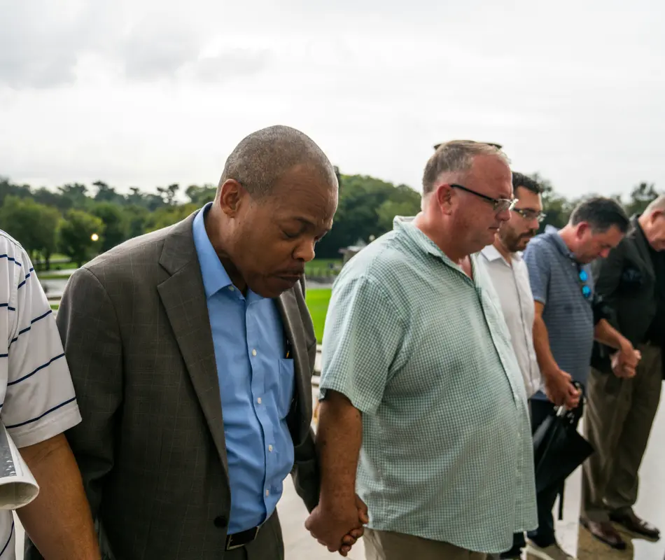Group praying outside holding hands